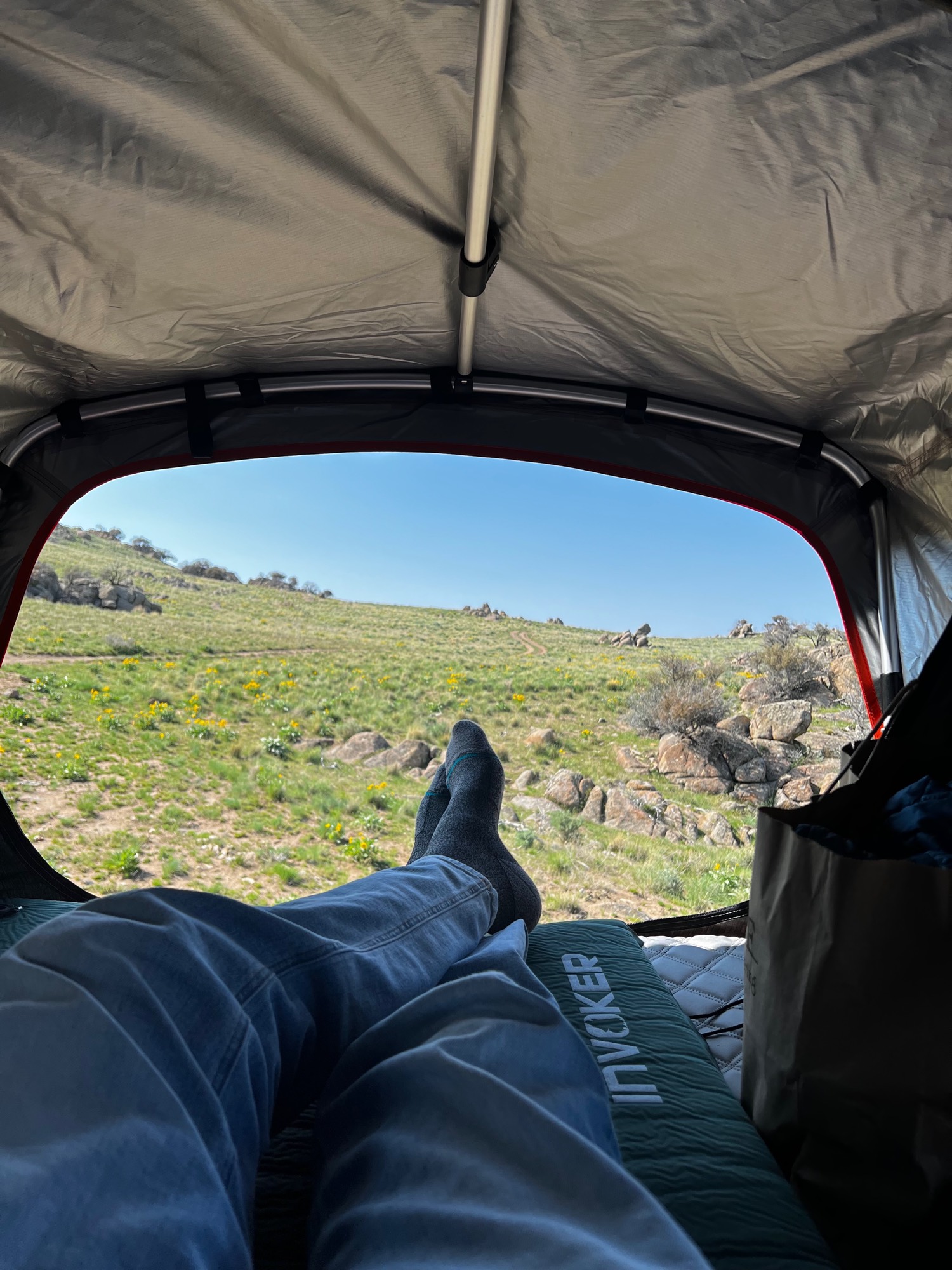 The view out of a rooftop tent across an empty hillside